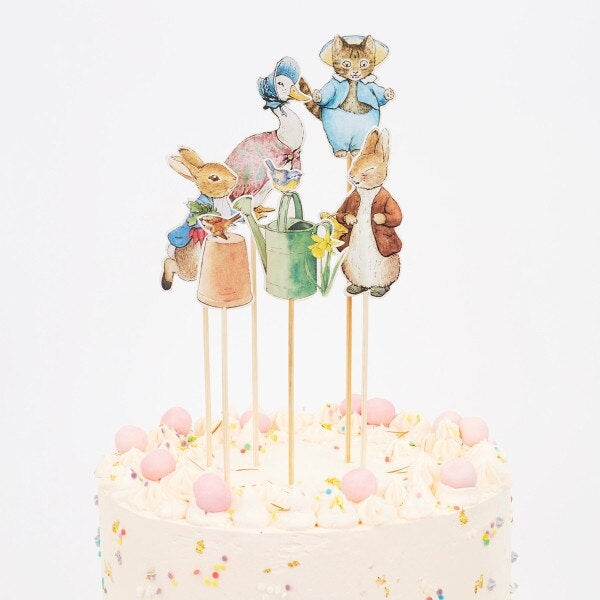 Cake topper with animated paper Peter Rabbit characters on sticks against a white background. Party decorations for a Peter Rabbit themed birthday.