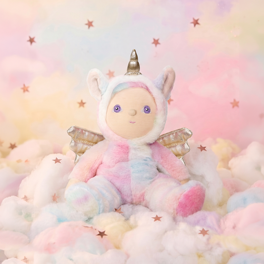 Stuffed toy in a unicorn costume on a soft, cloud-like surface with a pastel starry background.