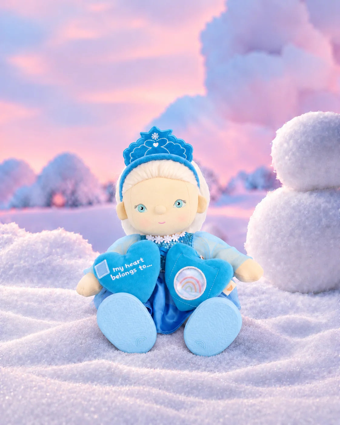 Olli Ella Dream Dinkum Doll Elsie Ice seated with her posable body holding magnetic heart locket in snowy winter wonderland scene