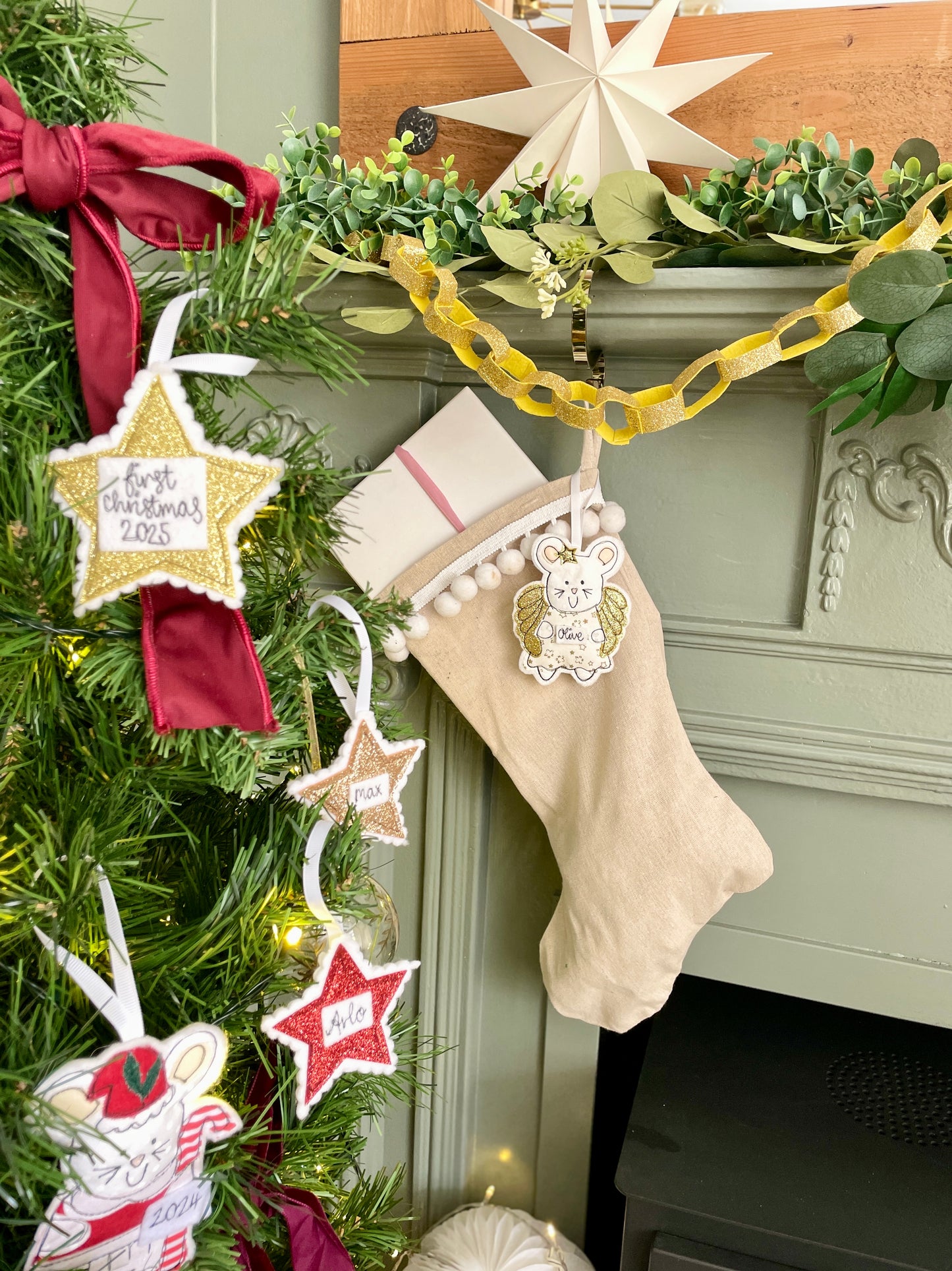 Christmas stocking hanging on a fireplace with decorative stars and ribbons with a Childs first Christmas personalised star Christmas tree decoration, hand embroidered