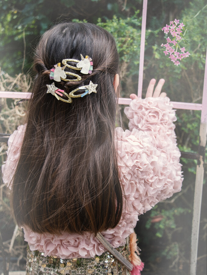 Child with long hair wearing colourful Rockahula hair clips in a garden setting featuring shooting star hair clips 