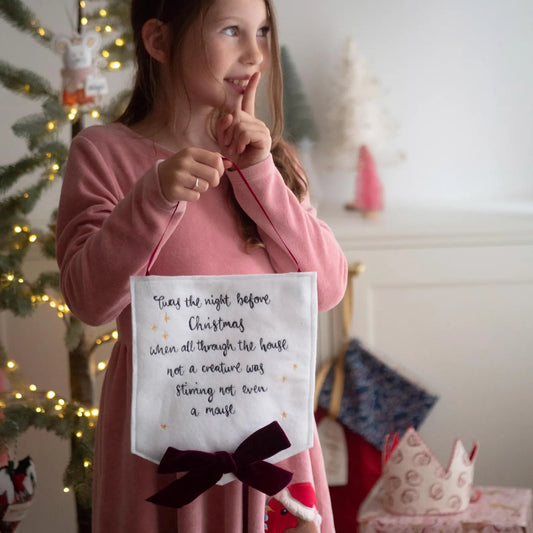 Girl holding a keepsake Christmas banner with the quote Twas the night before Christmas, a hand embroidered sign by Girl Friday Embroidery at Mouse in a Box