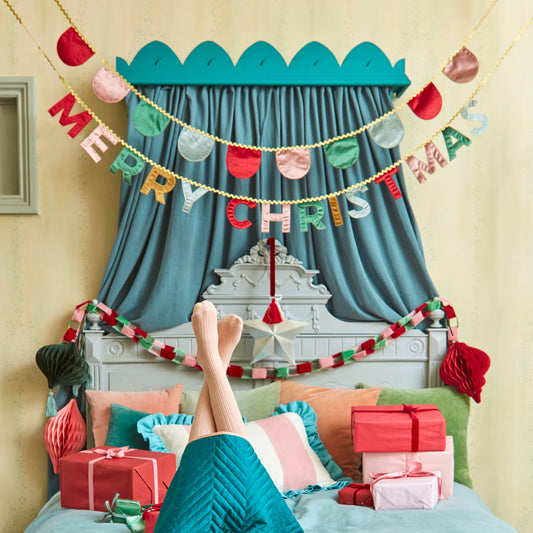 Decorated bedroom with Christmas decorations, including a 'Merry Christmas' banner and presents.

